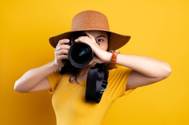 Yel üzerinde fotoğraf makinesiyle duran şapkalı kadın.