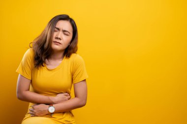 Kadının karın ağrısı sarı arka planda izole edilmiş.