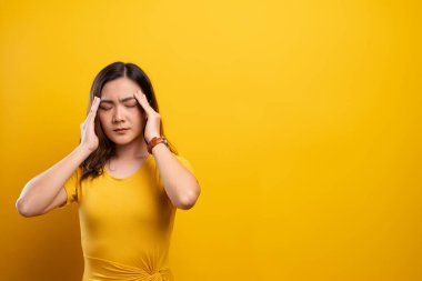 Kadının baş ağrısı sarı arka planda izole edilmiş.