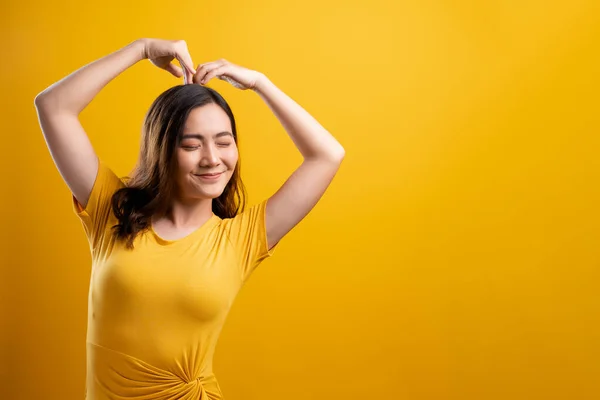 Vrouw in liefde tonen hart geïsoleerd over gele achtergrond — Stockfoto