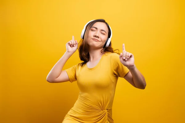 Femme avec écouteurs écoutant de la musique sur fond jaune isolé — Photo