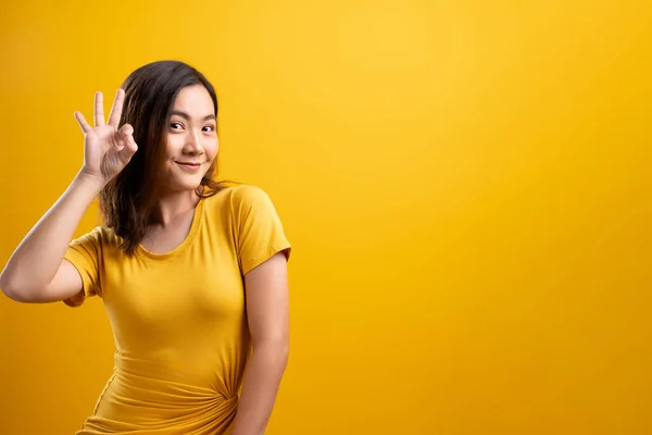 Happy woman showing OK gesture isolated on yellow background — Stock Photo, Image