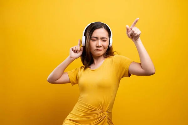 Femme avec écouteurs écoutant de la musique sur fond jaune isolé — Photo