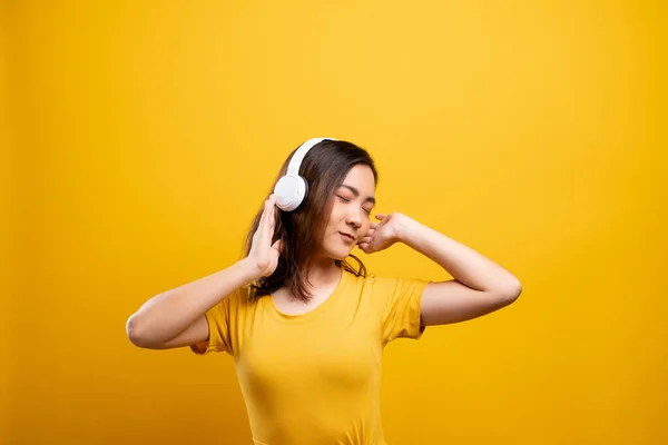 Kvinna med hörlurar lyssnar musik på isolerad gul backgro — Stockfoto