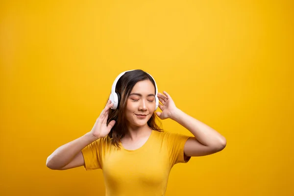 Kvinna med hörlurar lyssnar musik på isolerad gul backgro — Stockfoto