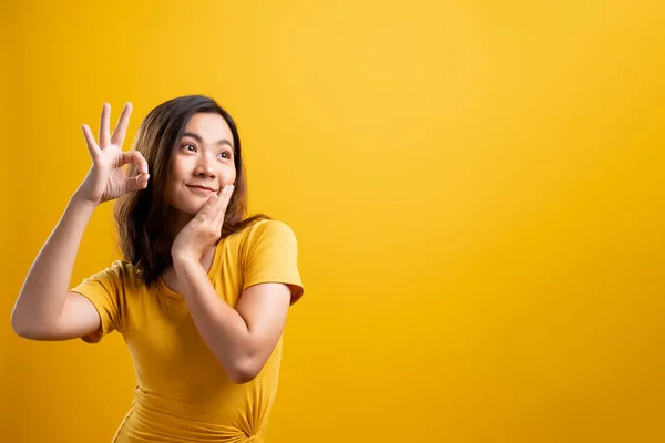 Счастливая женщина показывает хороший жест на желтом фоне — стоковое фото