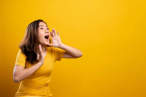 Happy woman making shout gesture isolated over yellow background — ストック写真