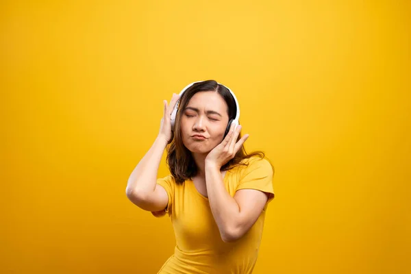 女性とともにヘッドフォンリッスン音楽上の隔離された黄色のバックグロ — ストック写真