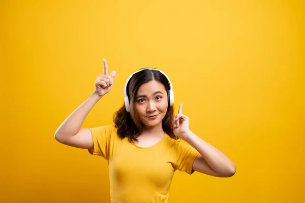 Mulher com fones de ouvido ouvindo música no backgro amarelo isolado — Fotografia de Stock