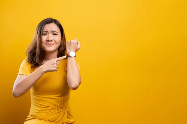 Shocked woman holding hand with wrist watch isolated on a yellow — Stock Photo, Image