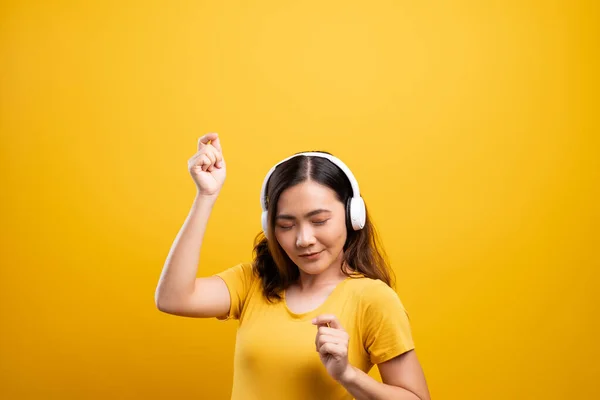 Femme avec écouteurs écoutant de la musique sur fond jaune isolé — Photo