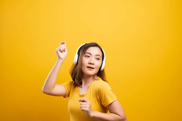 Женщина с наушниками слушает музыку на изолированной желтой backgro — стоковое фото