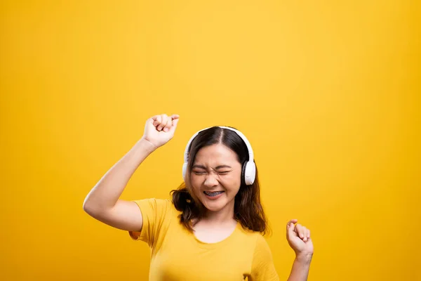 Femme avec écouteurs écoutant de la musique sur fond jaune isolé — Photo