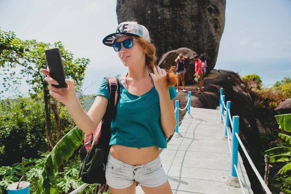 young stylish hipster ginger woman making selfie against mountai