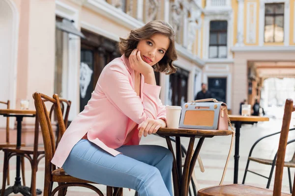 青いジーンズとピンクのジャケットを着たテーブルに座ってロマンチックな気分のきれいな女性 スタイリッシュなアパレル 夢を見て カフェでのデートでボーイフレンドを待っています ヨーロッパでの休暇 — ストック写真