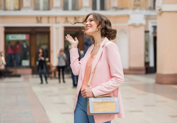 気楽な気分の女性は休暇で街を歩く ピンクのジャケットに身を包んだ エレガントな夏のスタイル ハンドバッグを保持し 彼女の髪を振って 肯定的な気分 — ストック写真