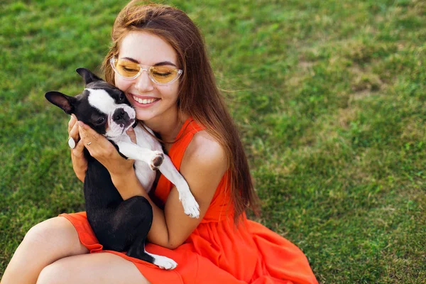 公園で犬と遊ぶ楽しいオレンジのドレスの若い幸せな笑顔の女性 夏のスタイル 陽気な気分 — ストック写真