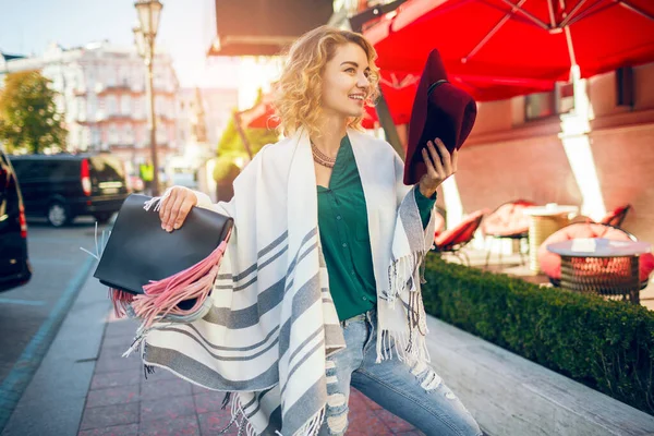美しいスタイリッシュな女性がケープホールディングハンドバッグ ファッションアクセサリー 春のストリートスタイルトレンド 笑顔で街を歩く — ストック写真