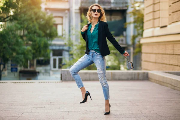 穿着高跟鞋 穿着蓝色牛仔裤 黑色夹克 绿色衬衫 太阳镜 手握小包 时尚潮流 苗条美丽的女士在城市街道上漫步的迷人优雅女人 — 图库照片