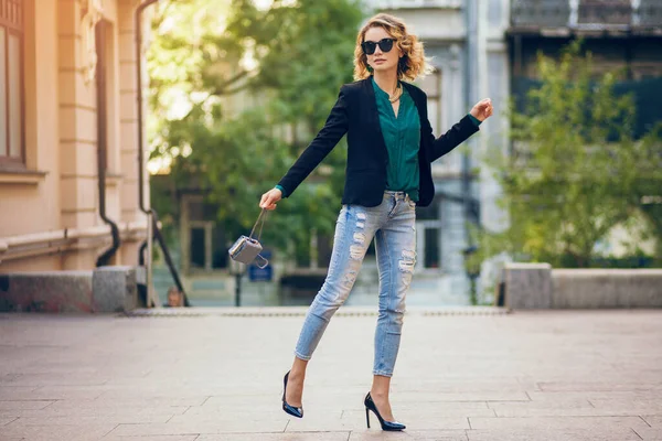 穿着高跟鞋 穿着蓝色牛仔裤 黑色夹克 绿色衬衫 太阳镜 手握小包 时尚潮流 苗条美丽的女士在城市街道上漫步的迷人优雅女人 — 图库照片