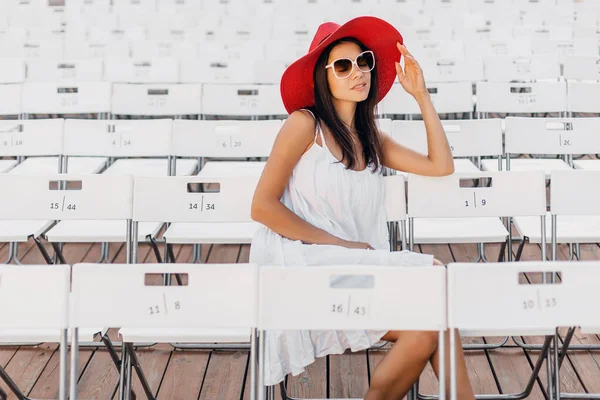Atraktivní Žena Oblečená Bílých Šatech Červený Klobouk Sluneční Brýle Sedí — Stock fotografie