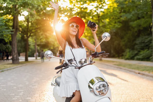 路上でバイクに乗って魅力的な女性 夏休みのスタイル 楽しみを持っています スタイリッシュな衣装 ヴィンテージ写真カメラで写真を撮る 手を振って — ストック写真