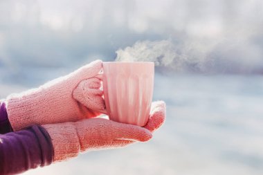Pembe eldivenleri fincan sıcak çay veya kahve ile tutan kadın elinde. Yakın çekim. Kış ve Noel zaman kavramı