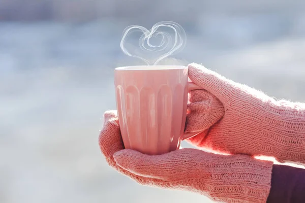 女手拿着杯热茶或咖啡与心形状的手套关闭 — 图库照片