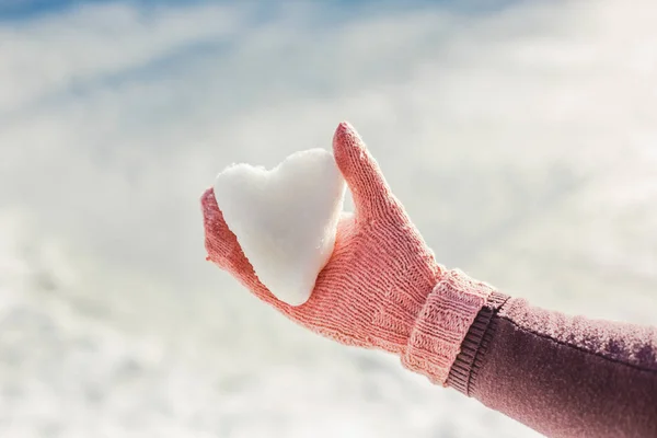 Hand in pink glove holding snow heart — Stock Photo, Image