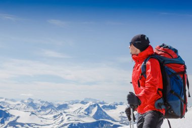 Uzun yürüyüşe çıkan kimse bir dağın tepesinde duran ve tne manzarayı sırt çantası ile