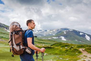 Uzun yürüyüşe çıkan kimse ayakta ve tne manzarayı sırt çantası ile