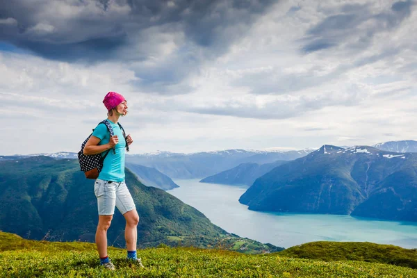 Young woman traveler standing on the top and looking into the distance — Stock Photo, Image