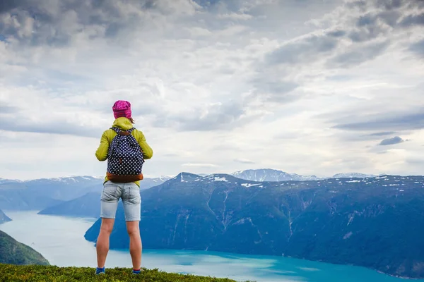 Young woman traveler standing on the top and looking into the distance — Stock Photo, Image