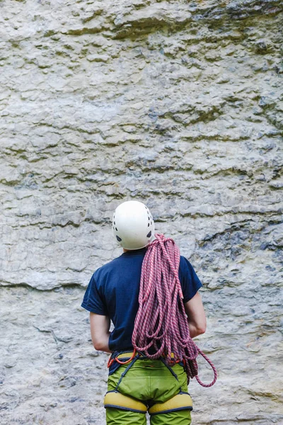 登山装備で石の岩の前に立って、登山ロープを身に着けている若い男 — ストック写真