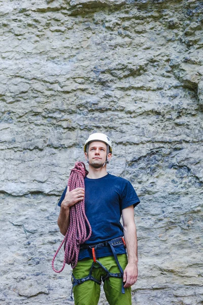 Jeune homme portant en équipement d'escalade avec corde debout devant un rocher de pierre et se préparant à grimper — Photo