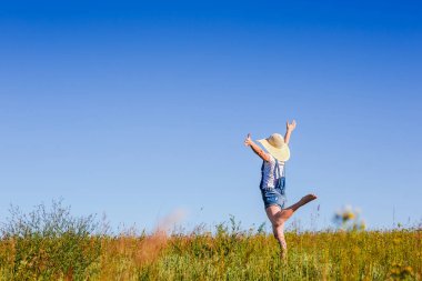 Mutlu kadın mavi gök yeşil alandaki atlama şapkalı. Yaz tatil kavramı