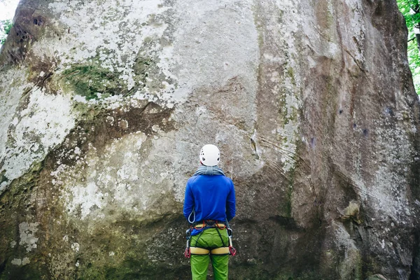 Молодой человек в альпинистском снаряжении с веревкой, стоящей перед каменной скалой и готовый к восхождению — стоковое фото