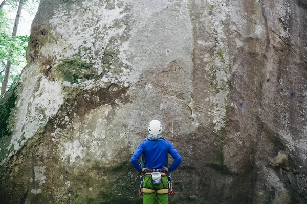 Jeune homme portant en équipement d'escalade avec corde debout devant un rocher de pierre et se préparant à grimper — Photo