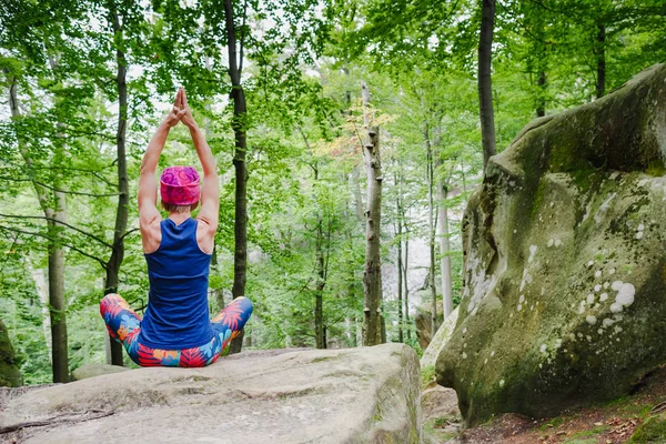 Mujer meditando en pose de loto, haciendo yoga sobre una roca en el bosque — Foto de Stock
