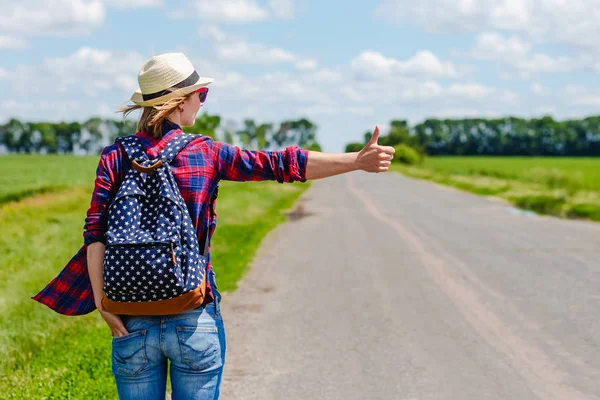 Κορίτσι με καπέλο και σακίδιο hitchhiking στο δρόμο — Φωτογραφία Αρχείου