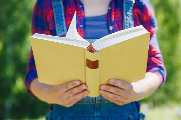 Руки крупным планом женщины держат книгу на открытом воздухе — стоковое фото