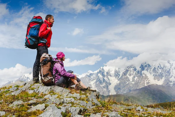 Mladý pár s batohy Turistika v horách a těší výhledem do údolí — Stock fotografie