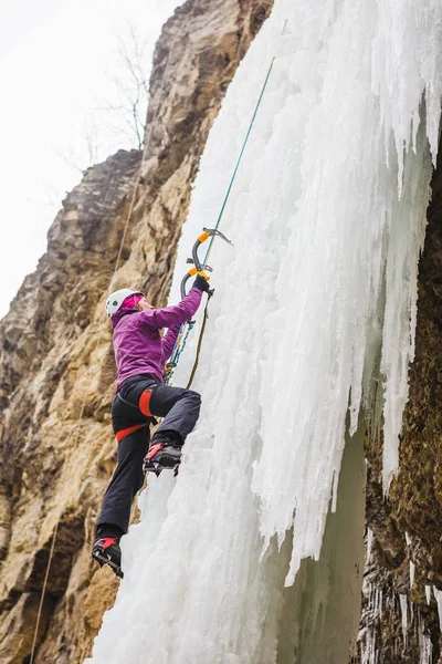 凍った滝を登る若い女性登山家 — ストック写真