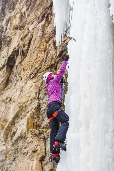 凍った滝を登る若い女性登山家 — ストック写真