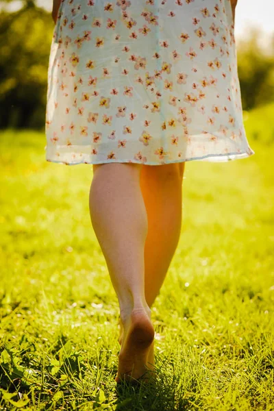 Jovem mulher no vestido andando no prado com grama verde — Fotografia de Stock