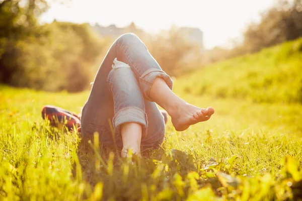 Молодая хипстерша лежит на траве на закате летнего времени — стоковое фото