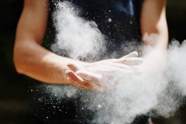 Climber woman coating her hands in powder chalk magnesium. Ready for climbing clipart