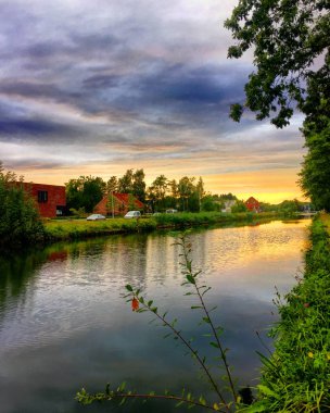 Nehri renkleri ile dramatik günbatımı suya yansıyan