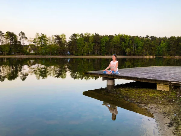 Mujer joven practica yoga y medita en la posición de loto — Foto de Stock