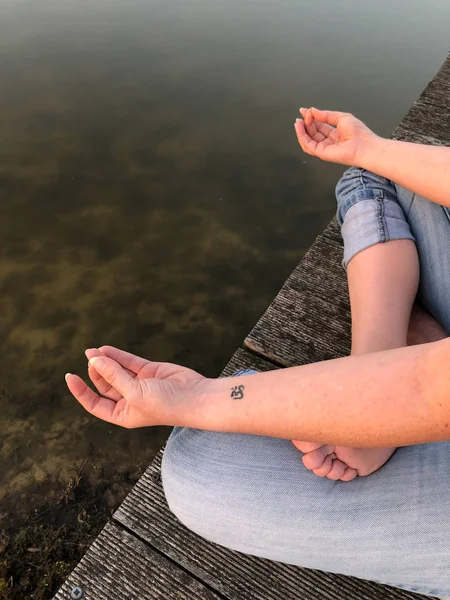 Mujer joven practica yoga y medita en la posición de loto — Foto de Stock